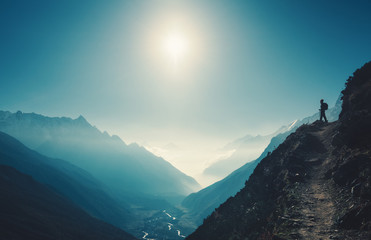 Wall Mural - standing woman on the hill against mountain valley at bright sunny day. landscape with girl, trail, 