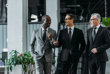Smiling Multiracial Businessmen Having Conversation While Walking In Office