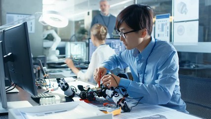 Wall Mural - Electronics Engineer Works with Robot Checking Voltage and Program Response time. Computer Science Research Laboratory with Specialists Working.