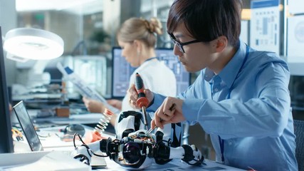 Wall Mural - electronics engineer works with robot, soldering wires and circuits. computer science research labor