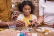 © LIGHTFIELD STUDIOS - cropped image of african american parents and daughter painting easter eggs