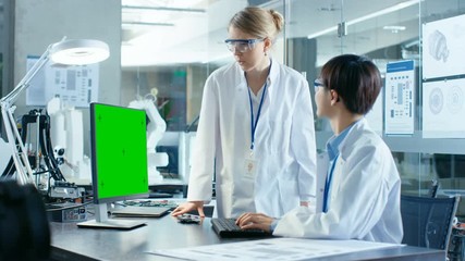 Wall Mural - asian scientist sitting at his desk consults senior engineer while working on a green screen persona