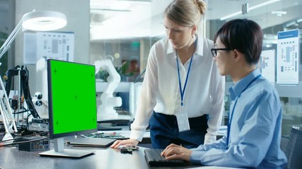 Wall Mural - asian scientist sitting at his desk consults senior engineer while working on a green screen persona