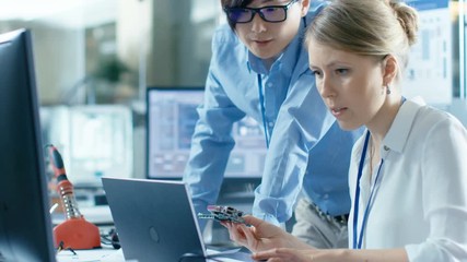 Wall Mural - female computer scientists connects circuit board to her laptop and starts programming it. she works