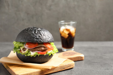 Wall Mural - Tasty burger with black bun on table