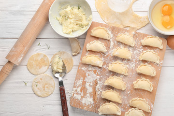 Wall Mural - Raw dumplings with potato on wooden board, top view