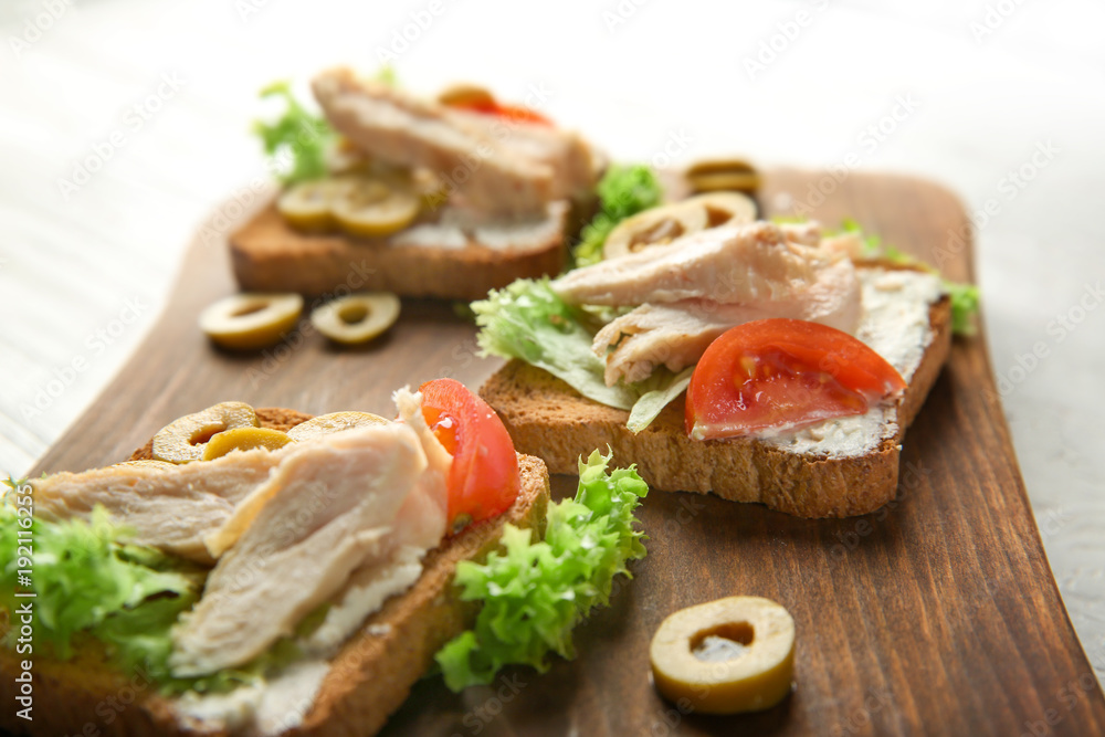 Wooden board with tasty chicken bruschettas, closeup