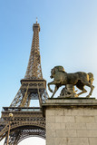 Fototapeta Boho - Low angle view of the Eiffel tower in Paris, seen from the Iena bridge against blue sky, with an equestrian stone statue in the foreground.
