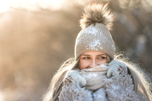 Close Portrait Of Young Caucasian Woman With Long Hair In Beige Hat With Fur Pompon, Scarf, Coat, White Gloves Covered With Snow At Sunny Winter Day, / Female Wrap In And Holding Scarf, Copy Space