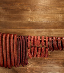 Wall Mural - Composition of different type of sausage hanged on wooden background