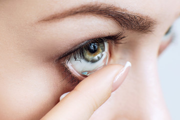 Close-up shot of young woman wearing contact lens.