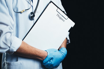 The doctor on a black background, in the hands of the folder where the inscription diagnosis as a template place for text