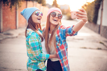 Wall Mural - Two young women are taking selfie on the street.