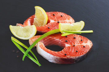 Slice of red fish salmon with lemon and rosemary isolated on black background