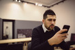 © Nebojsa - Serious businessman using phone while working on laptop.