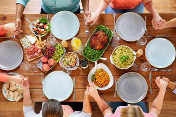 Wall Mural - group of people at table praying before meal