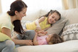 © Oksana Kuzmina - Smiling kids and their mom having a fun pastime on sofa in living room at home
