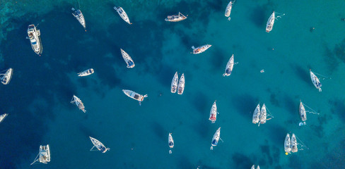 aerial view of many anchoring yacht in open water.