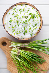 Bowl of cream cheese with green onions, dip sauce on wooden table.