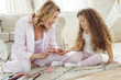 mother and daughter in pajamas making manicure at home