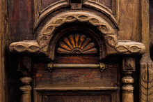 Vintage Background. Elements Of An Old Carved Wooden Door Decorated With Voluminous Carved Wooden Elements Imitating The Weaving. A Vintage Concept Of Old Antiques. Varnished Old Mahogany