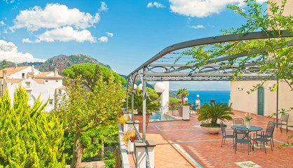 Wall Mural - villa terrace with table and flowers overlooking sea and mountains