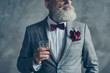 © deagreez - Cropped close up photo of confident pensive financier wearing classic modern elegant luxury clothing with burgundy handkerchief estimating the taste of whisky isolated on grey background