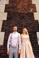 Wall Mural - the couple in love stands on the background of a brick wall and look at the camera lens