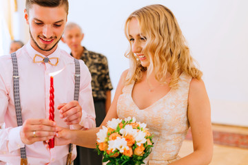 Wall Mural - the bride and groom light up a candle and the bride holds a bouquet in the bright room