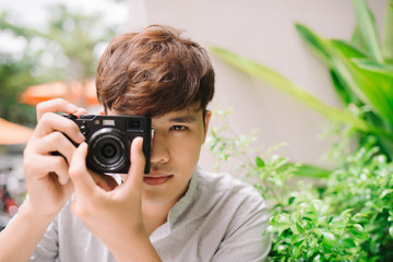 Wall Mural - Young man photographer taking picture sitting at table in coffee shop