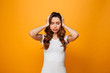 © Drobot Dean - Confused brunette woman in t-shirt holding her head