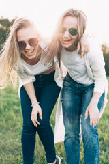 Wall Mural - Two young women are having fun on the green field in the evening.