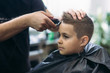 © Aleksandr - Professional hairdresser uses a hair clipper for fringing hair for a small boy