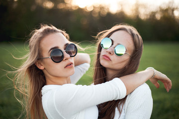 Wall Mural - Two young women are posing on the field in the evening.