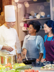 Wall Mural - happy women and chef cook cooking in kitchen