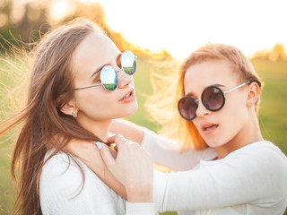 Wall Mural - Two cheerful women hugging outdoors at spring. Close up