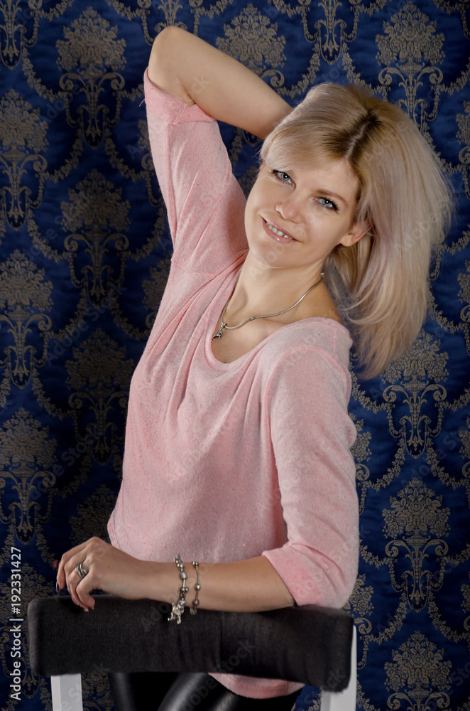 Portrait of a beautiful blonde woman in a pink jacket and leather pants ...