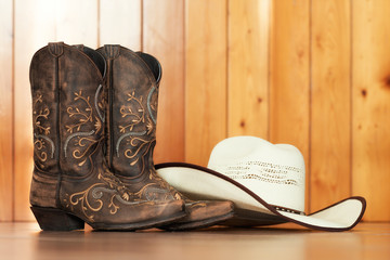 cowgirl embroidered boots and white hat on wooden background - text space