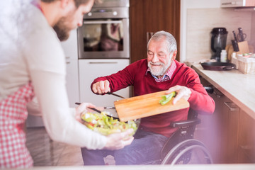 Wall Mural - Son and senior father in wheelchair cooking in the kitchen.