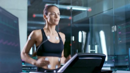 Wall Mural - beautiful woman athlete with electrodes attached to her, running on a treadmill in a sports science 