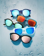Sunglasses Frames With Colorful Lenses Against Background With Water Drops