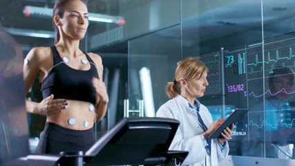 Wall Mural - beautiful woman athlete runs on a treadmill with electrodes attached to her body, female physician u