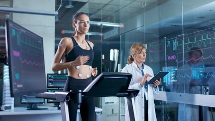 Wall Mural - beautiful woman athlete runs on a treadmill with electrodes attached to her body, female physician u