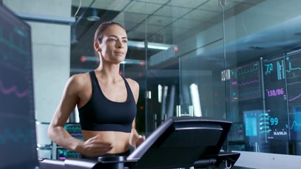 Wall Mural - beautiful woman athlete wearing sport bra, running on a treadmill in a sports science laboratory. in