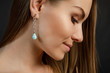 красивое лицо в профиль молодой женщины с серьгой в ухе из драгоценного голубого камня  