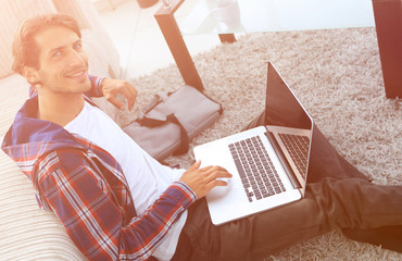 Wall Mural - business guy with laptop sitting on carpet in living room.