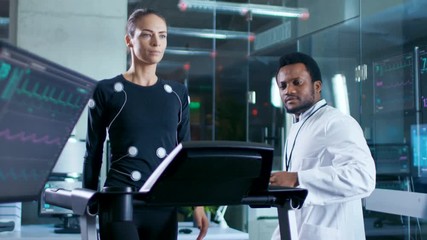 Wall Mural - in scientific sports laboratory beautiful woman athlete walks on a treadmill with electrodes attache