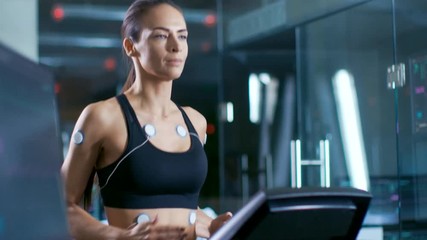 Wall Mural - in scientific sports laboratory beautiful woman athlete runs on a treadmill with electrodes attached