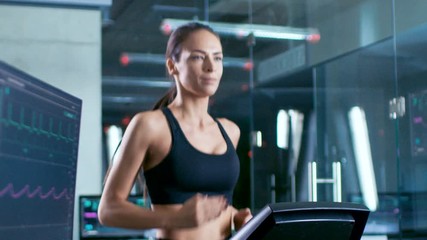 Wall Mural - in scientific sports laboratory beautiful woman athlete walks on a treadmill with electrodes attache