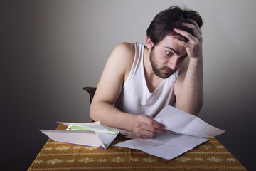 Young man shocked and terrified with the amount of money for his bills